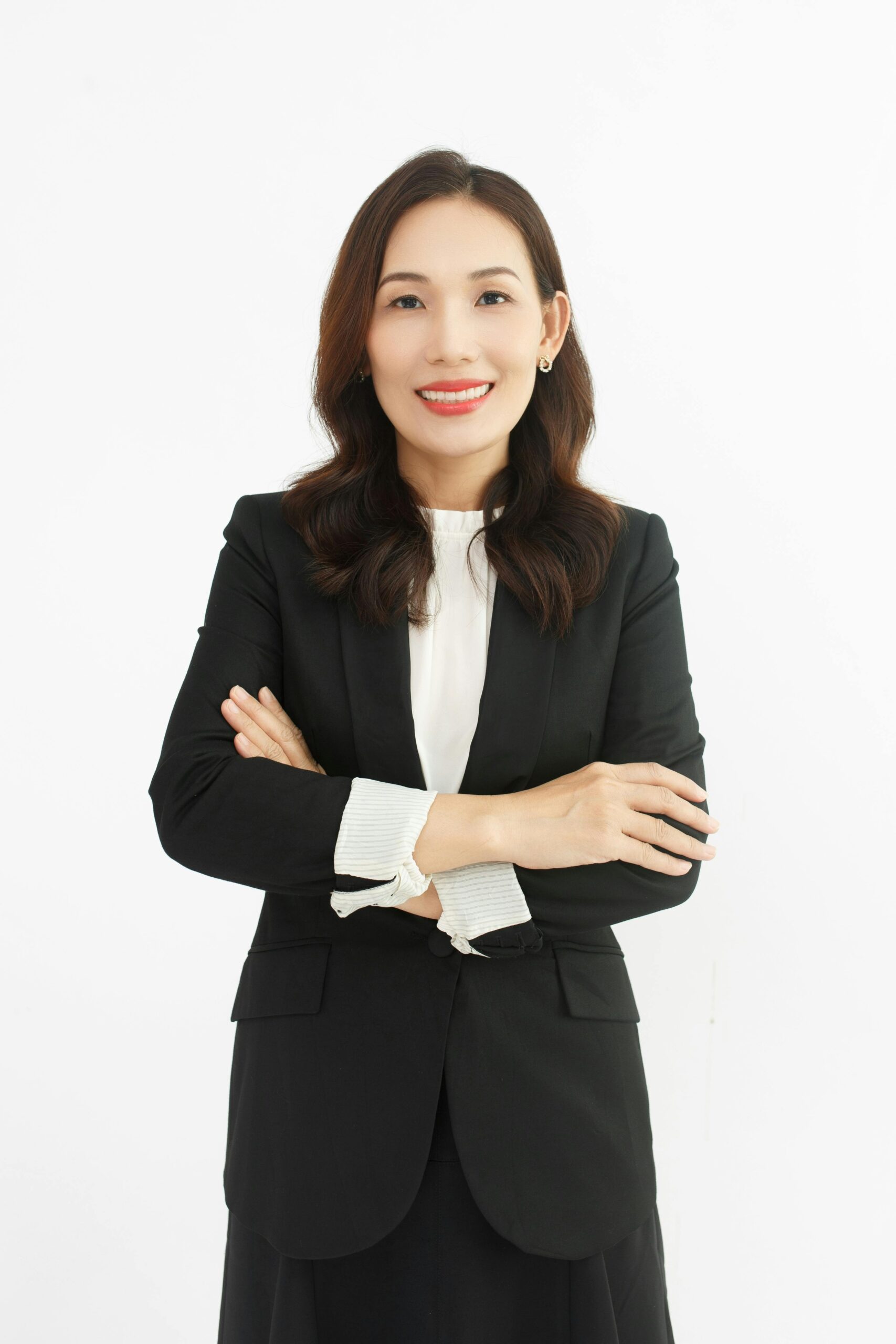 Professional portrait of a confident businesswoman in a black suit against a white background.