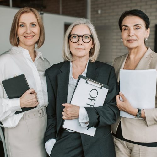 Group of senior female professionals confidently posing in office setting.